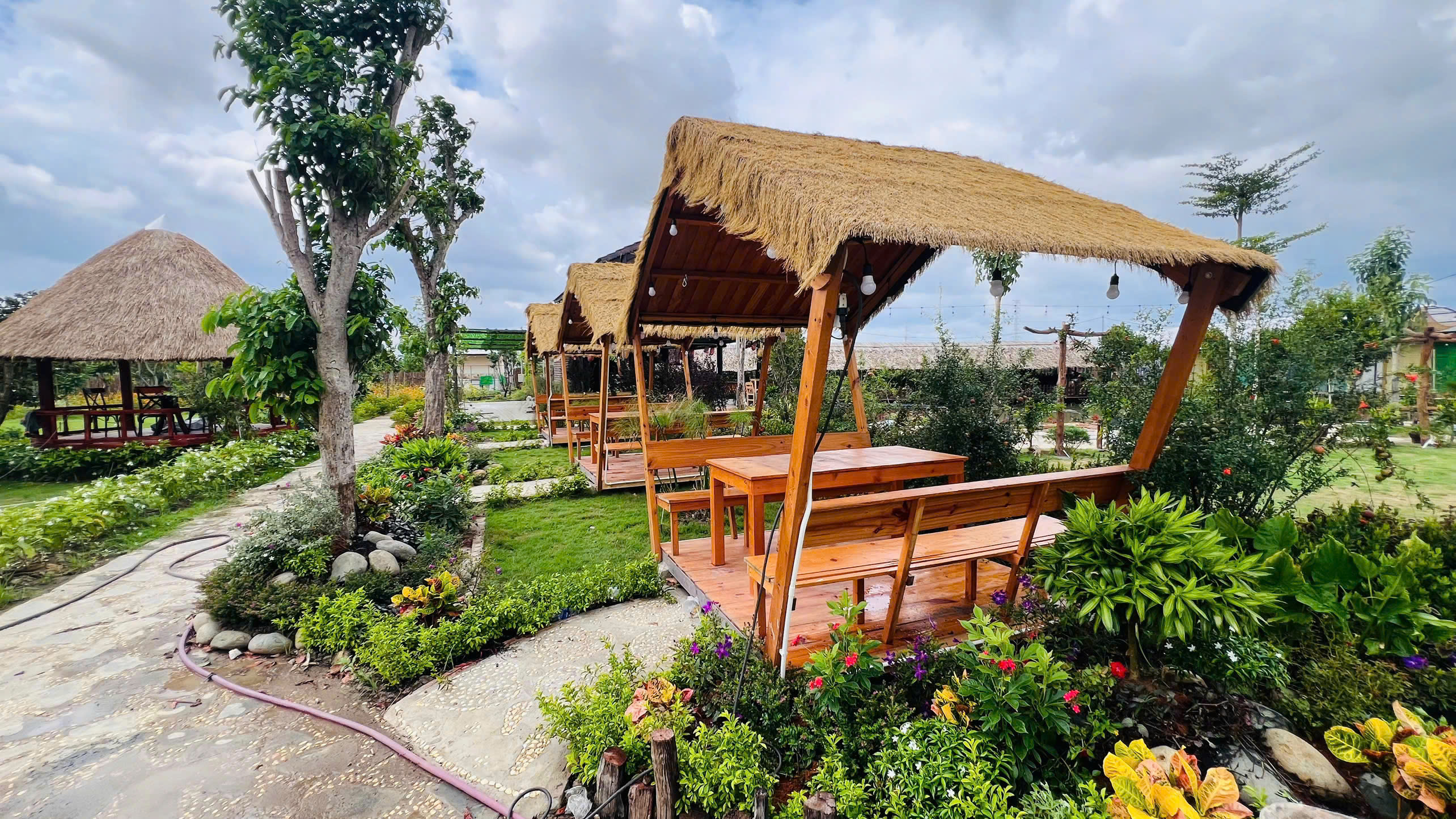 Dãy chòi ăn uống mái lá ven hồ rực rỡ hoa cỏ tại Sen Vàng Garden Hóc Môn
